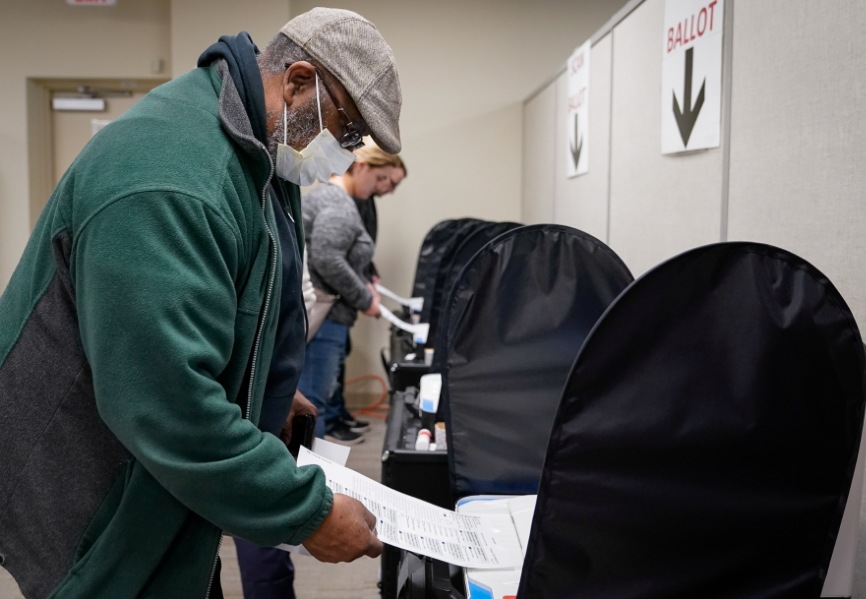 A voter wearing a protective face mask casts a ballot in the United States. REUTERS.