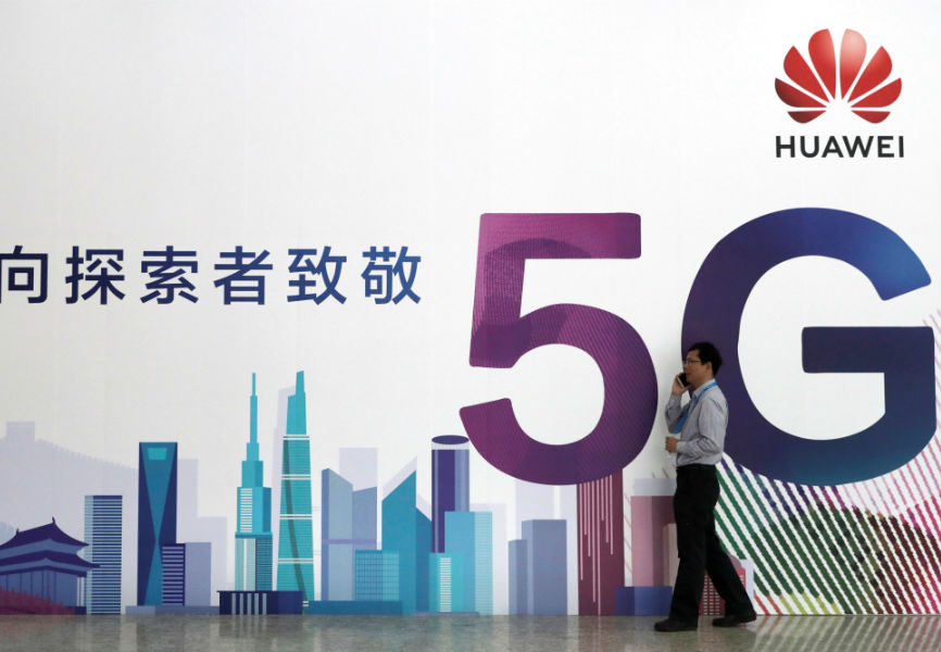 A man talks on his phone beside a Huawei billboard featuring 5G technology at the PT Expo in Beijing. REUTERS.