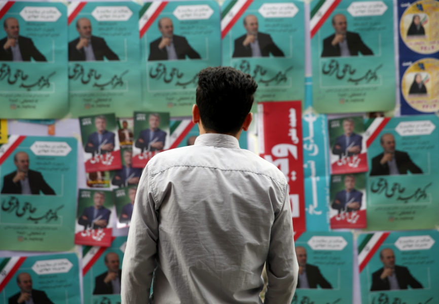 A man looks at Iranian parliamentary election campaign posters in Tehran. REUTERS.