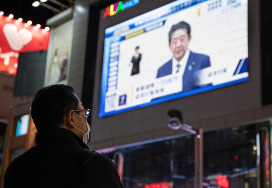 A man watches Japanese Prime Minister Abe Shinzo's 7 April 2020 press conference announcing a state of emergency. REUTERS.