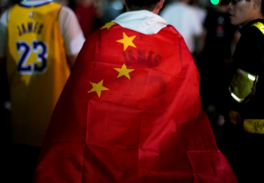 A basketball fan wraps himself in a Chinese flag before an NBA exhibition game between the Brooklyn Nets and Los Angeles Lakers in Shanghai. REUTERS.