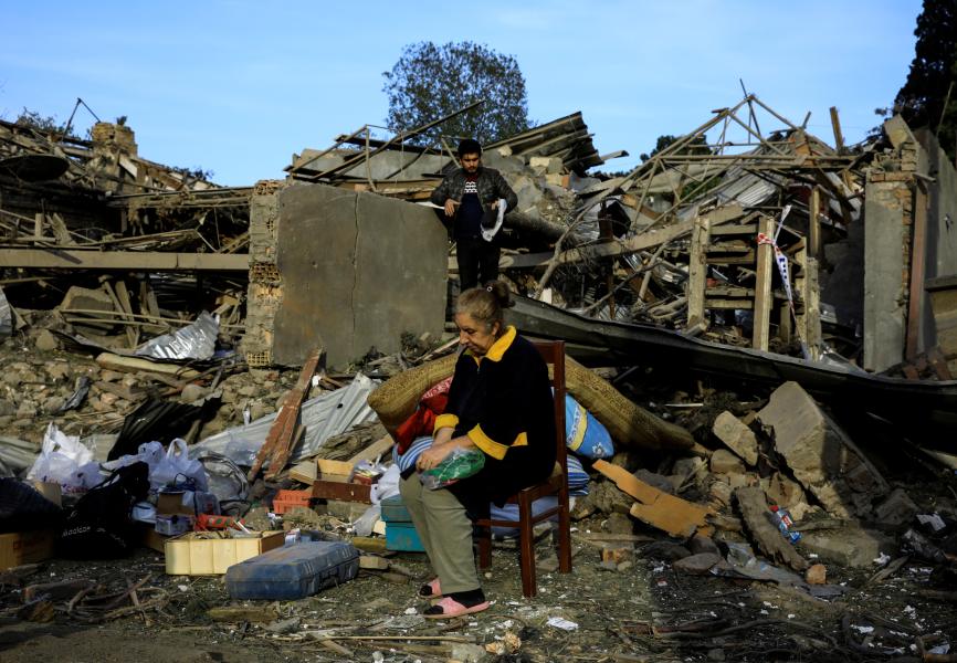 A woman sits outside a home hit by a rocket in Ganja, Azerbaijan during fighting between Azerbaijan and Armenia over the Nagorno-Karabakh region. REUTERS.