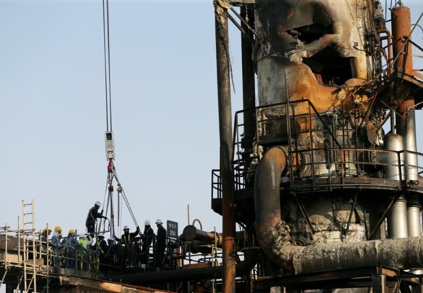 Workers at a damaged Saudi Aramco oil facility. REUTERS.