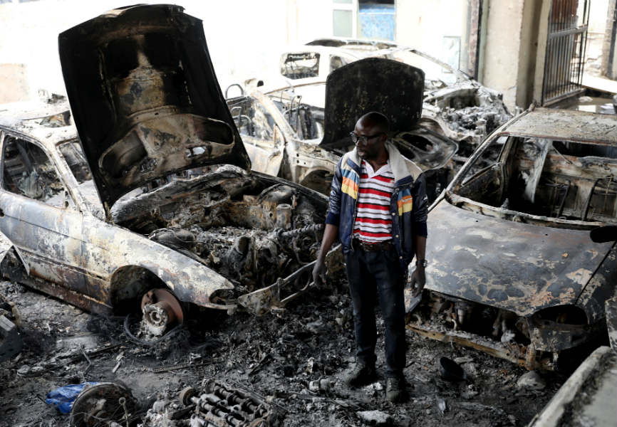 A Nigerian entrepreneur surveys damage to his car dealership in Johannesburg after xenophobic attacks. REUTERS.