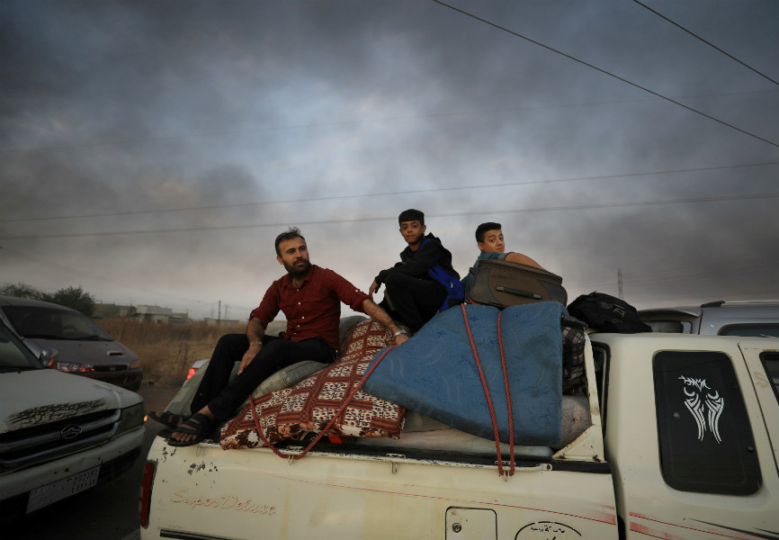 People flee Ras al-Ain, a town in northeast Syria hit by Turkish attacks. REUTERS.